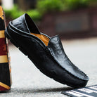 Black leather loafer shoe on a textured surface with a blurred background