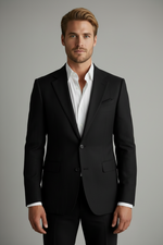 Man wearing a black suit jacket over a white shirt on a gray background