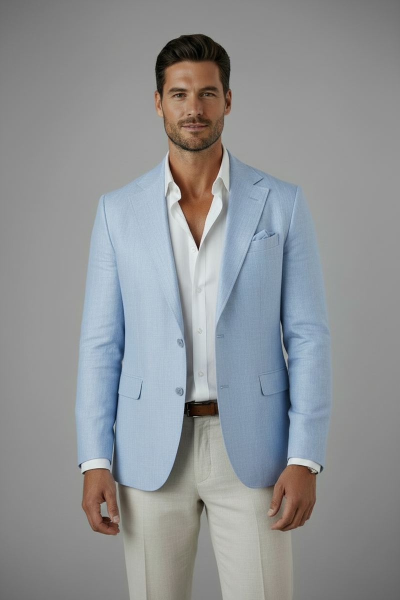 Man wearing a light blue blazer over a white shirt with beige pants on a gray background