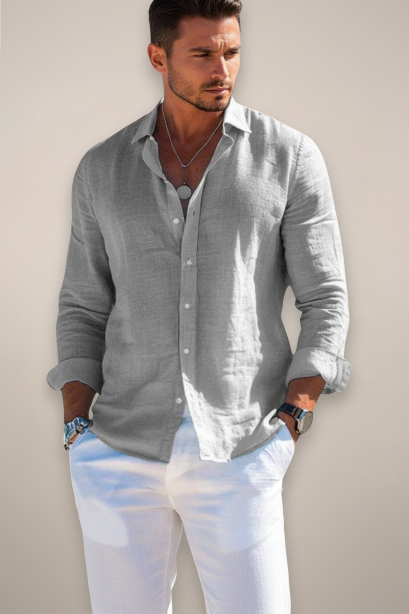 Man wearing a light gray button-up shirt with rolled-up sleeves against a plain background