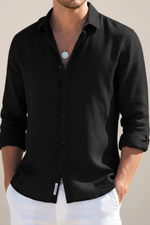 Man wearing a black button-up shirt with a neutral background