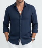 Man wearing a blue button-up shirt with a neutral background