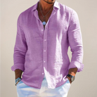Man wearing a purple button-up shirt with rolled-up sleeves against a plain background