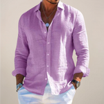 Man wearing a purple button-up shirt with rolled-up sleeves against a plain background