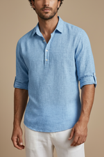 Man wearing a blue linen shirt with rolled-up sleeves on a beige background
