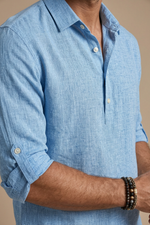 Close-up of a person wearing a light blue shirt with rolled-up sleeves.