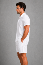 Man wearing a white polo shirt and shorts against a gray background