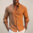 Man wearing a brown button-up shirt with rolled-up sleeves against a neutral background