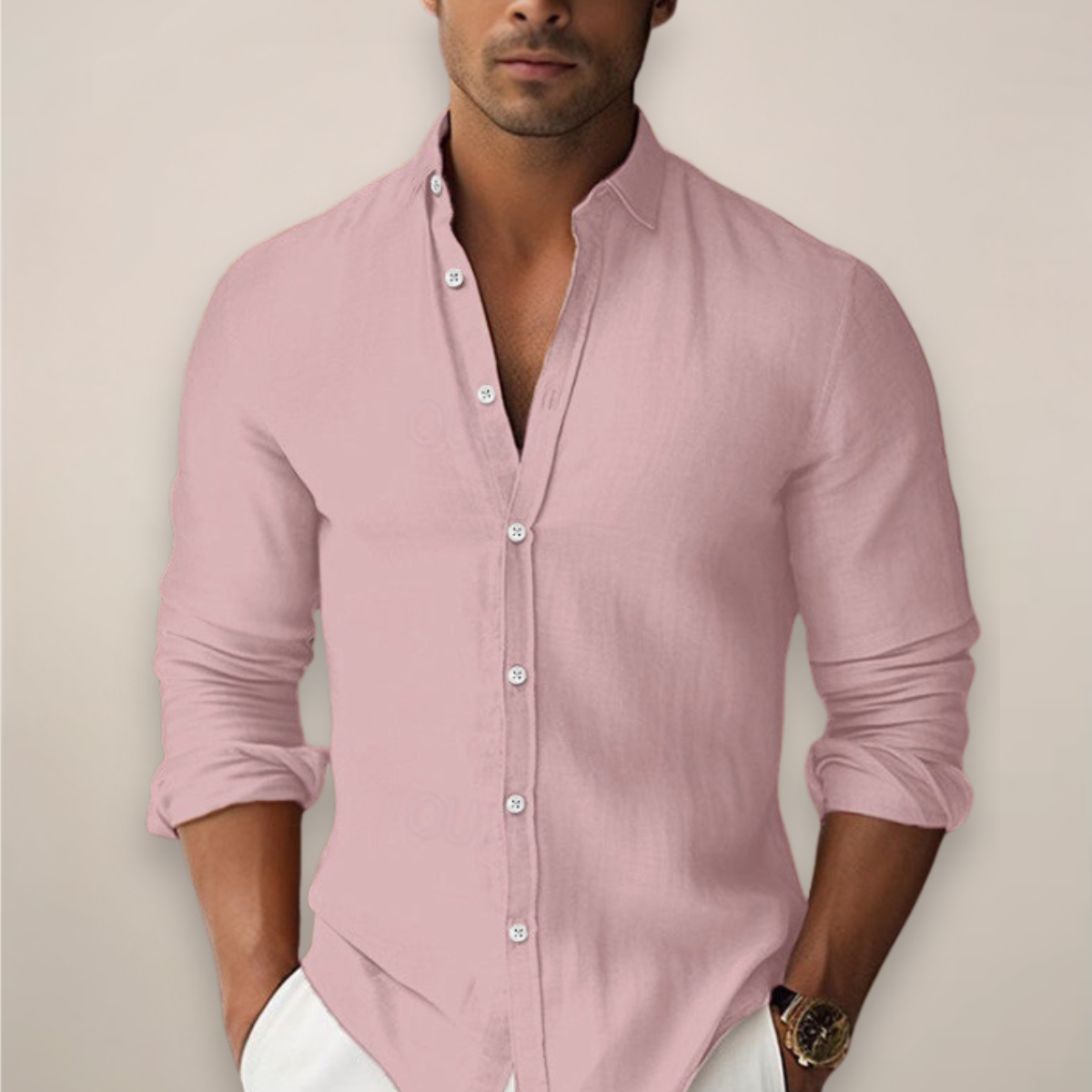 Man wearing a light pink button-up shirt with rolled-up sleeves against a plain background
