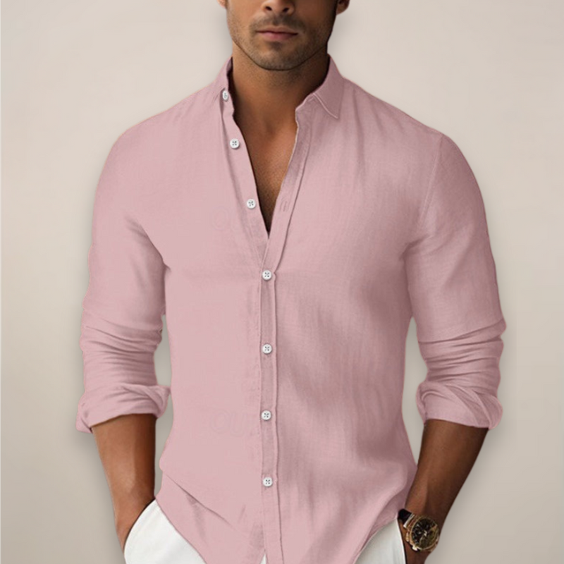 Man wearing a light pink button-up shirt with rolled-up sleeves against a plain background