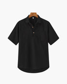 Black short-sleeve shirt on a hanger against a white background