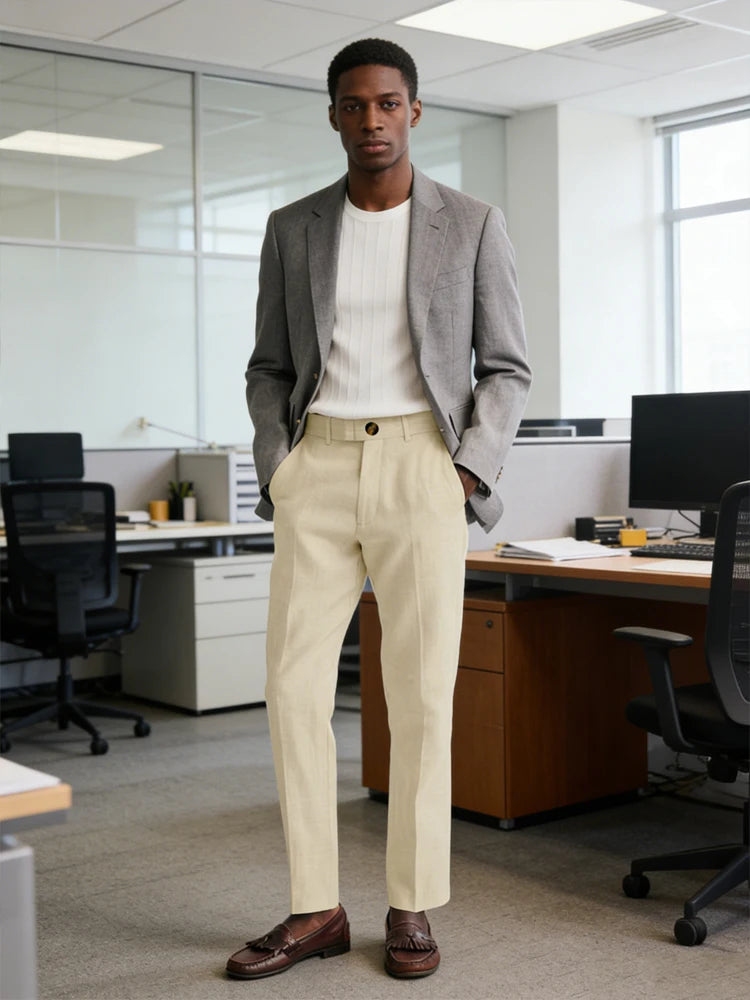Man in a gray blazer and beige pants standing in an office setting