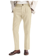 Beige dress pants worn with a white shirt and brown loafers on a white background