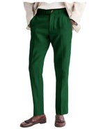 Green dress pants worn with a beige jacket and brown shoes on a white background