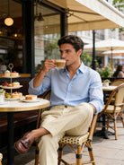 Man sitting at an outdoor cafe, sipping a cup of coffee.