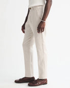 Person wearing beige pants and brown shoes on a white background