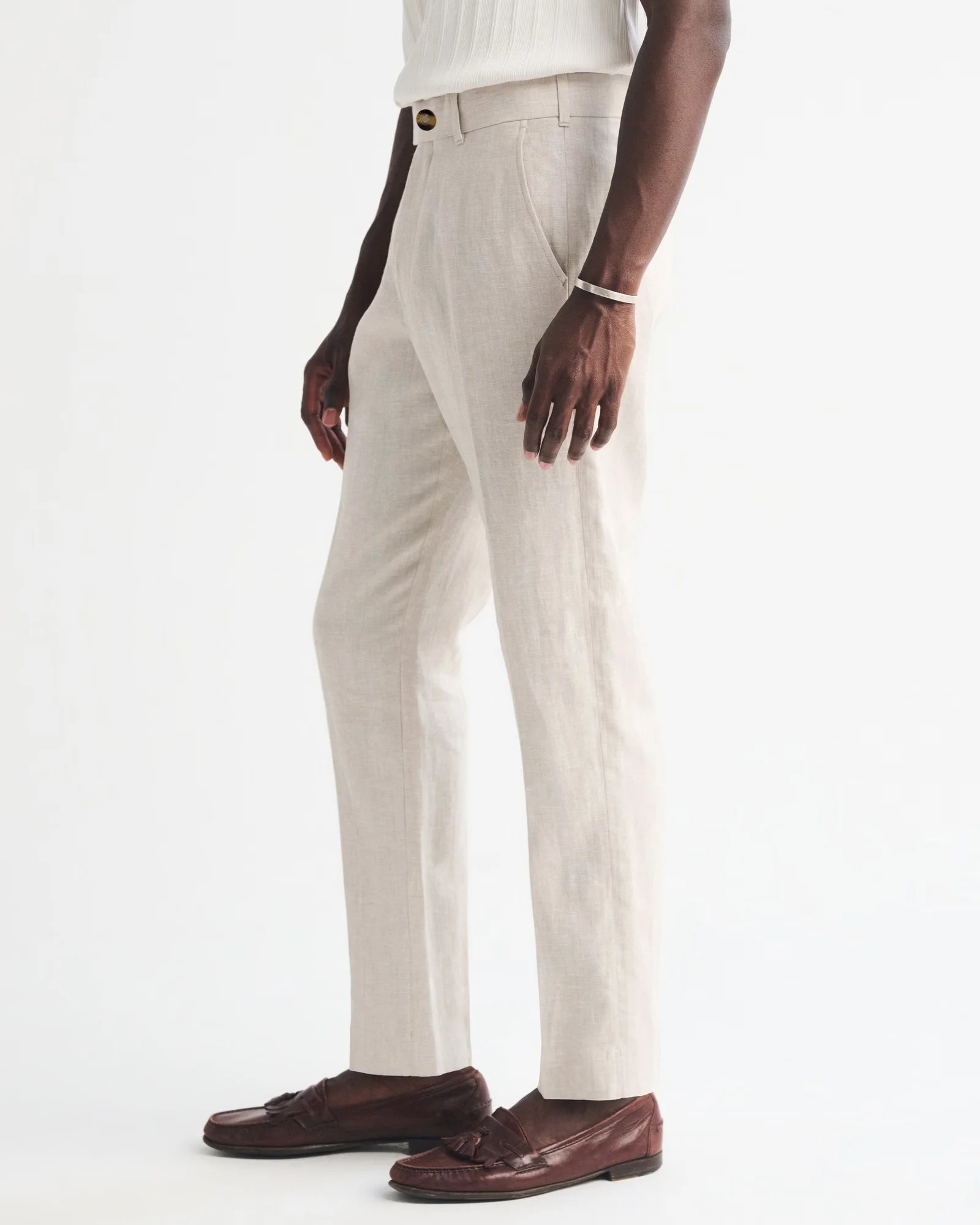 Person wearing beige pants and brown shoes on a white background