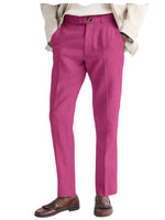 Pink trousers worn with a beige jacket and brown shoes on a white background