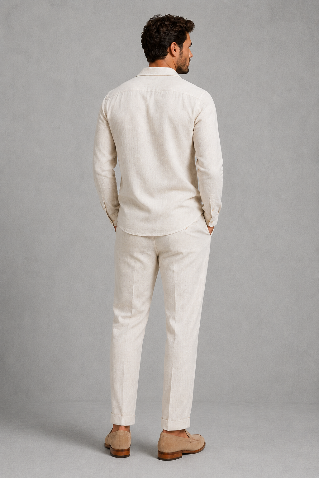 Man wearing a beige linen suit standing against a gray background