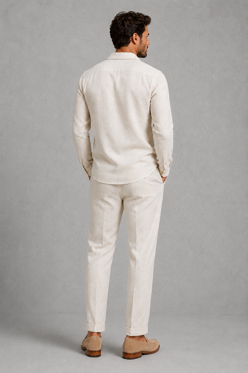 Man wearing a beige linen suit standing against a gray background