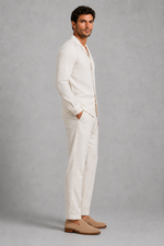 Man wearing a white linen suit with beige shoes on a gray background