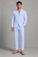 Man wearing a light blue linen suit with beige shoes on a gray background