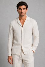 Man wearing a light-colored linen suit against a gray background