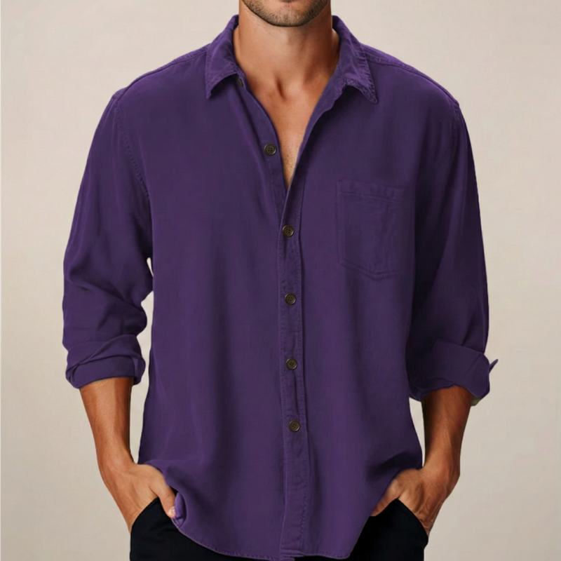 Man wearing a purple button-up shirt with rolled-up sleeves against a beige background