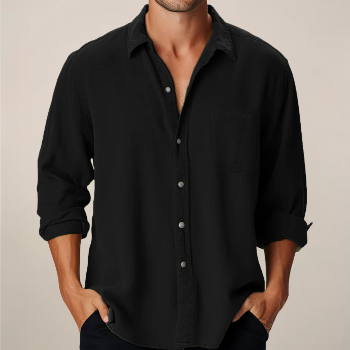 Man wearing a black button-up shirt with rolled-up sleeves against a beige background