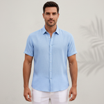 Man wearing a light blue short-sleeve shirt and white pants on a plain background
