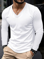 Man wearing a white long-sleeve shirt and beige pants with a blurred background