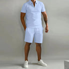 Person wearing a light blue polo shirt and shorts set with white sneakers on a plain background