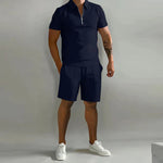 Person wearing a black polo shirt and shorts with white sneakers on a gray background