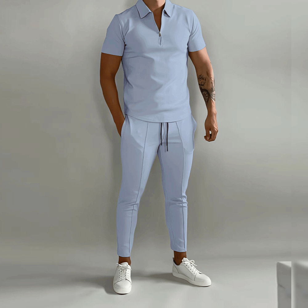 Man wearing a light blue outfit with white sneakers on a plain background