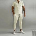 Person wearing a beige outfit with white sneakers on a gray background