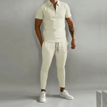 Person wearing a beige outfit with white sneakers on a gray background