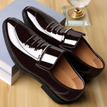 Shiny black loafers on a wooden surface