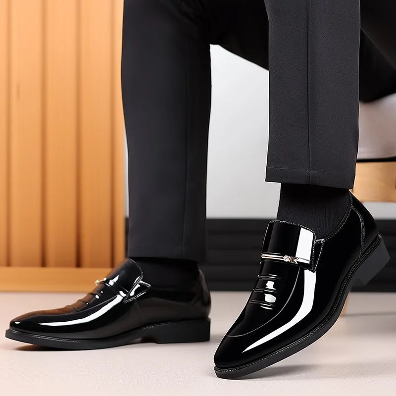 Black shiny dress shoes worn with black pants on a neutral background