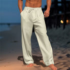 Person wearing light-colored pants standing on a beach at dusk.