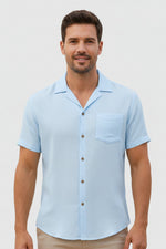 Man wearing a light blue short-sleeve shirt on a plain background