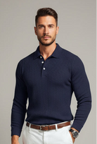 Man wearing a navy ribbed sweater over a white shirt with a blurred background