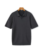 Black ribbed polo shirt on a hanger against a white background