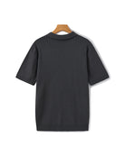 Black ribbed sweater on a wooden hanger against a white background