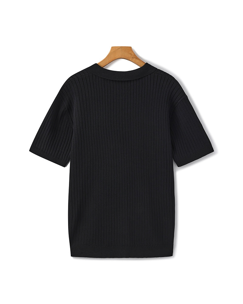 Black ribbed sweater on a wooden hanger against a white background