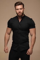 Man wearing a black short-sleeve shirt against a beige background