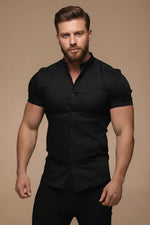Man wearing a black short-sleeve shirt against a beige background