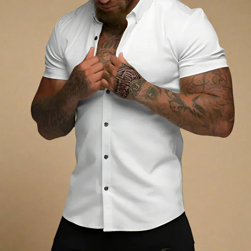 Man wearing a white short-sleeve button-up shirt against a beige background