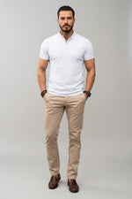 Man wearing a white polo shirt and beige pants against a gray background