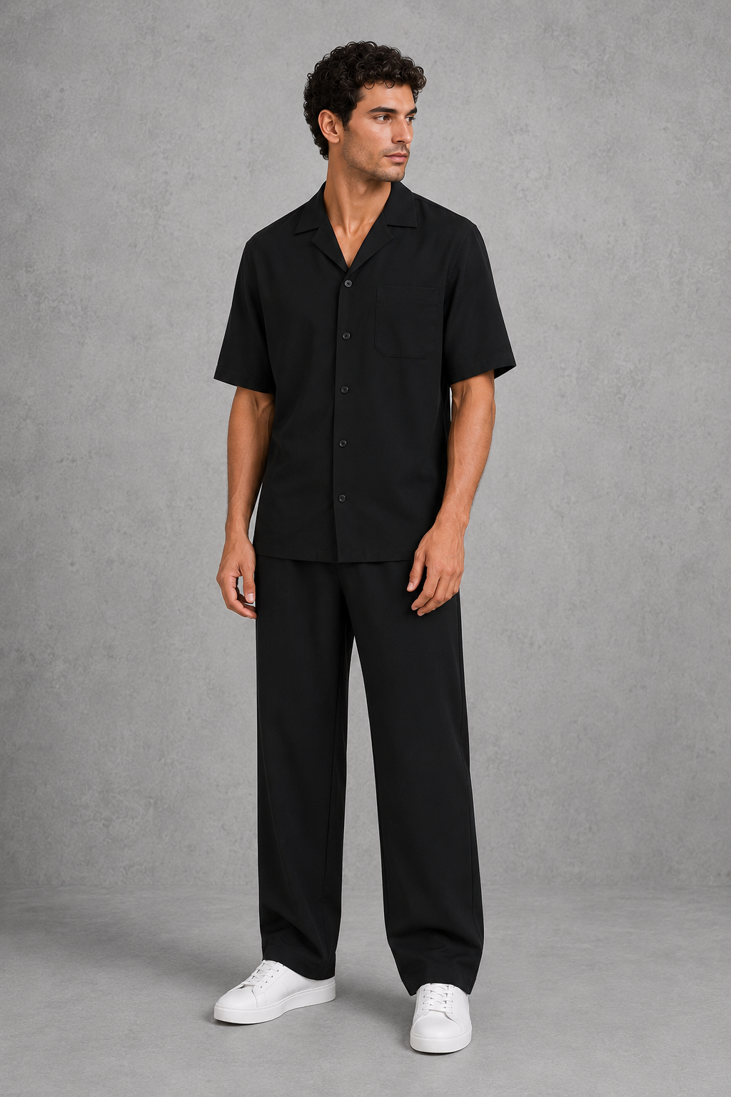 Man wearing a black outfit with white shoes on a gray background