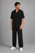 Man wearing a black outfit with white shoes on a gray background